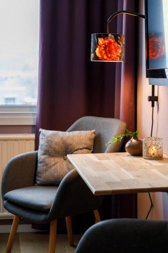 a chair sitting next to a table with a lamp at Hotell Nyboholm in Ulricehamn