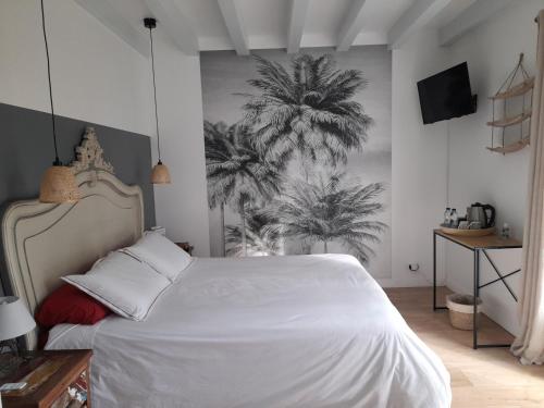 a bedroom with a white bed and palm trees on the wall at La Clairière du Seignanx in Saint-Martin-de-Seignanx