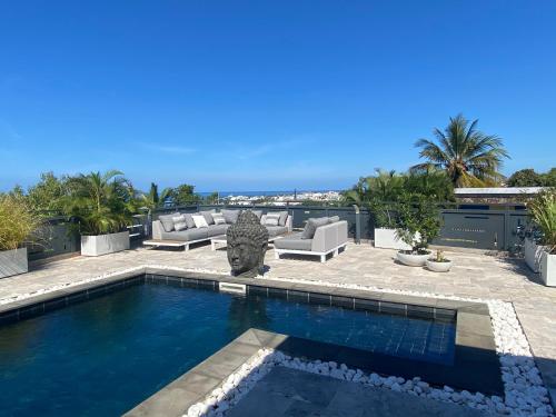 een zwembad in een tuin met een patio bij Villa L’Eden Zen face à l océan in Saint-Pierre