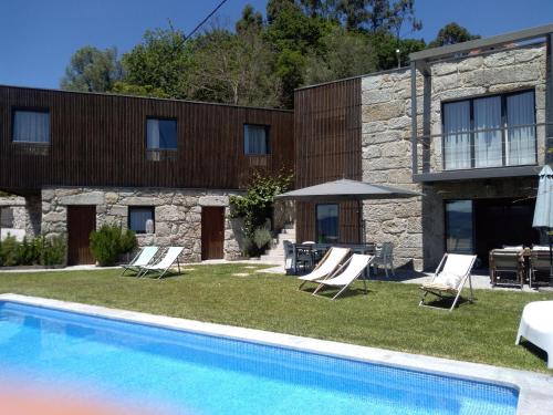 un complejo con piscina, sillas y un edificio en Casas da Li, en Arcos de Valdevez