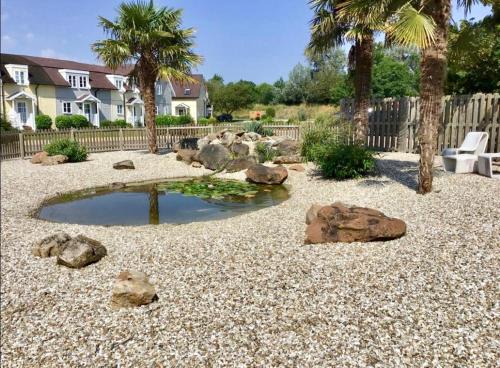 a garden with rocks and a pond in front of a house at Spinnaker Lodge · Cotswolds Lakeside Home in South Cerney