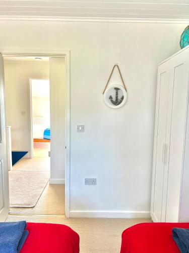 a white room with a red bed and a mirror at Spinnaker Lodge · Cotswolds Lakeside Home in South Cerney