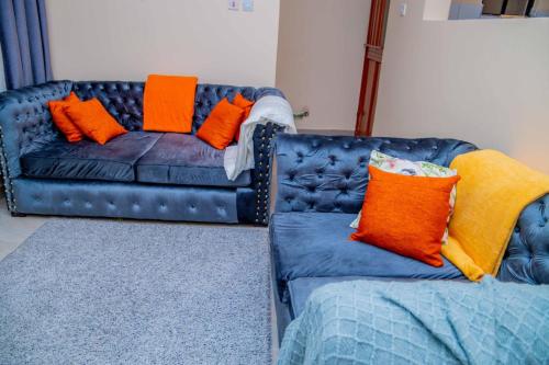 eine blaue Couch mit orangefarbenen und gelben Kissen darauf in der Unterkunft IT IS WELL HOMES in Kisii