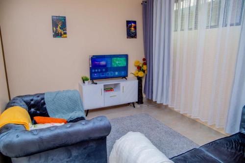 een woonkamer met een bank en een televisie bij IT IS WELL HOMES in Kisii