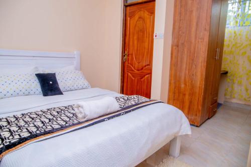 Schlafzimmer mit einem Bett und einer Holztür in der Unterkunft IT IS WELL HOMES in Kisii