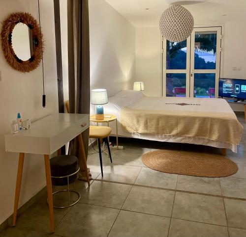 Schlafzimmer mit einem Bett, einem Tisch und einem Spiegel in der Unterkunft La Villa Trocas in Koungou