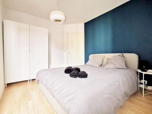 a bedroom with a white bed with a blue wall at Le Contemporain (Centre - Gare - Commerces) in Lens