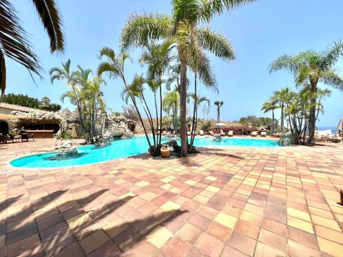 een zwembad met palmbomen in een resort bij Comfortable apartamento AP1, con piscina, cerca de Playa los Roques in Los Realejos