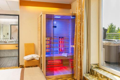 a glass shower in a room with a bed at Lotus Therme Hotel & Spa in Hévíz