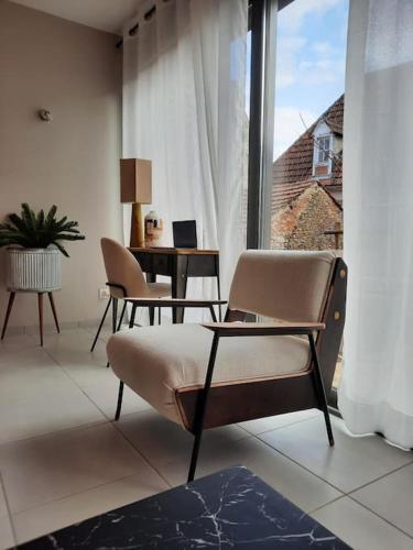 un salon avec une table et des chaises et une fenêtre dans l'établissement Le Spicy 2 minutes centre historique parking, à Sarlat-la-Canéda