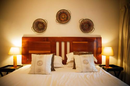a bedroom with a large white bed with two lamps at Honeywood Forest Lodge in Port Shepstone