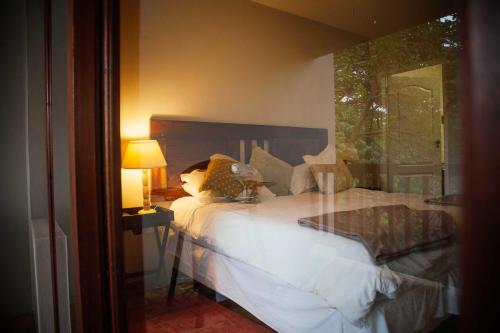 a bedroom with a white bed with a window at Honeywood Forest Lodge in Port Shepstone