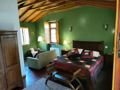 a bedroom with green walls and a bed and a chair at Quinta Padre Lobo in Santa Maria Da Feira