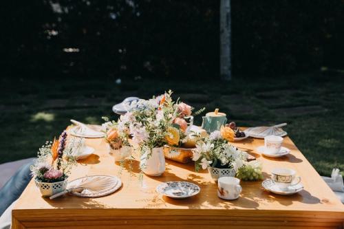 uma mesa com flores, copos e pratos em Bong Villa Hoi An - Vesta Collections em Hoi An