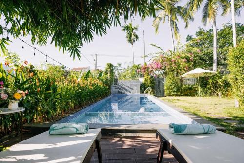 uma piscina num jardim com duas mesas em Bong Villa Hoi An - Vesta Collections em Hoi An