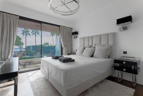 - une chambre avec un grand lit blanc et une grande fenêtre dans l'établissement Palais Des Iles - La Croisette, à Cannes