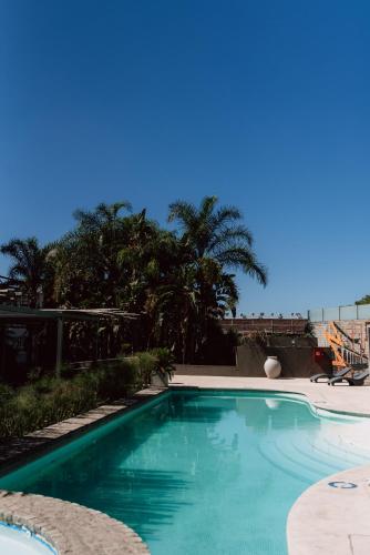 a swimming pool with blue water and palm trees at Hilton Garden Inn Tucuman in San Miguel de Tucumán