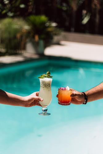 a person holding a drink and a dessert next to a pool at Hilton Garden Inn Tucuman in San Miguel de Tucumán