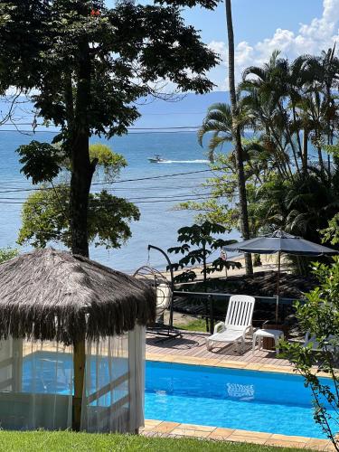 a resort swimming pool with a view of the ocean at La Bella Suítes in Ilhabela