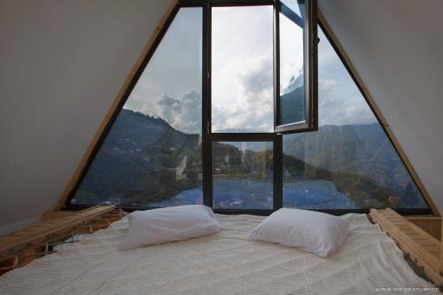 a bed with two pillows in front of a large window at Hill Wonder in Batumi