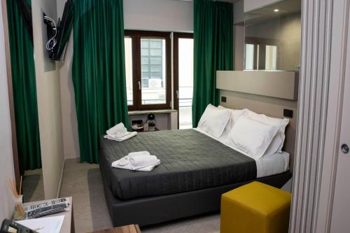 Un dormitorio con una cama con cortinas verdes y un taburete amarillo en Calypsosuite, en Salerno