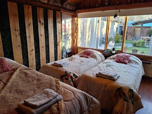 two beds in a room with a large window at Sentidos Cardinales in Perito Moreno