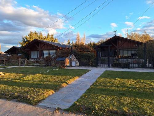 a house with a fence and a sidewalk in a yard at Sentidos Cardinales in Perito Moreno