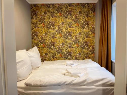 オルデンブルクにあるApartment Prinzessin Aphrodite - Zimmerprinzenの白いシーツと花柄の壁紙が貼られたベッド