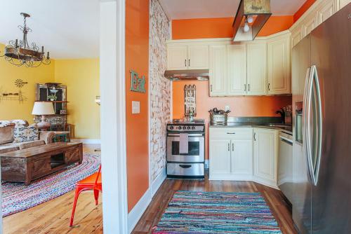una cocina con armarios blancos y una pared de color naranja en The Shenandoah Suite, en Staunton