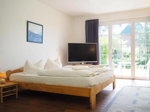 a bedroom with a large bed with a flat screen tv at Gästehaus - Residenz Kormoran in Prerow