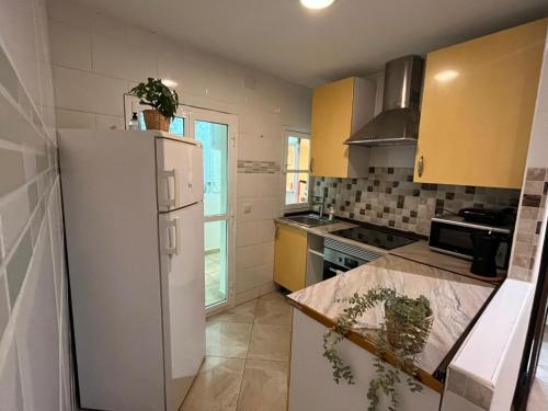 a kitchen with a white refrigerator and yellow cabinets at Apartamento familiar 3 habitaciones Alcala in Madrid