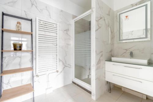 een witte badkamer met een wastafel en een spiegel bij Appartement neuf, lumineux & cosy proche La Défense, Neuilly & Paris in Puteaux