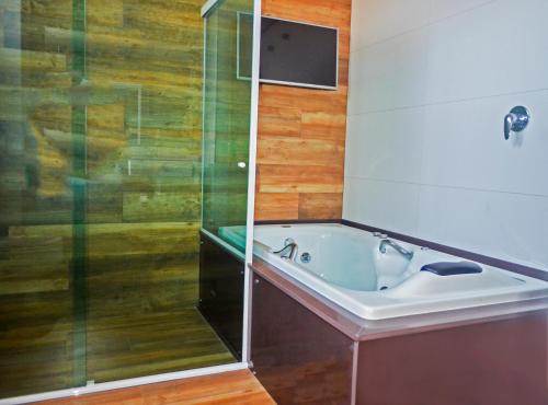 a bathroom with a tub and a glass shower at Pers Palace Hotel in Santa Inês