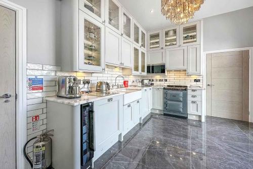 a large kitchen with white cabinets and a chandelier at Little Fox Lodge Luxury Hideaway with Hot Tub Glencoe Near Fortwilliam in Glencoe