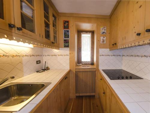 cocina con armarios de madera, fregadero y ventana en Villa Lucente, en Alvera