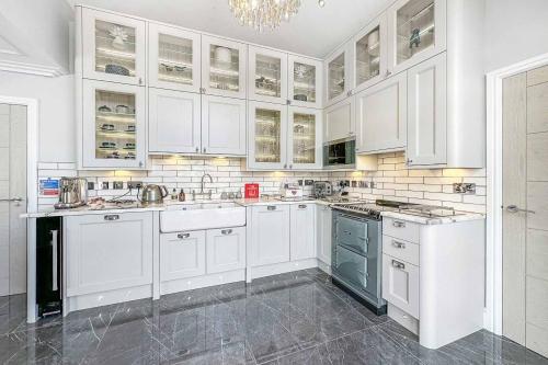 a white kitchen with white cabinets and appliances at Little Fox Lodge Luxury Hideaway with Hot Tub Glencoe Near Fortwilliam in Glencoe