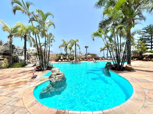 - une piscine dans un complexe avec des palmiers dans l'établissement Estandar un dormitorio con estupenda vista y piscina, Playa Los Roques, à Los Realejos
