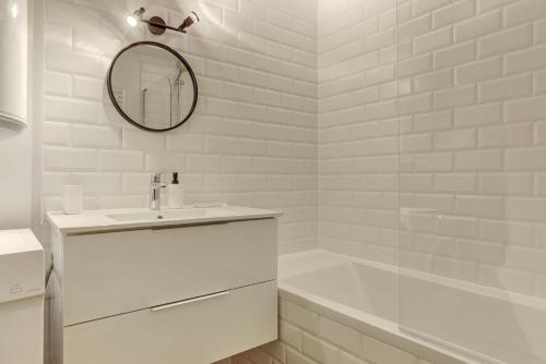 een witte badkamer met een wastafel en een spiegel bij Le Petit Nid - Montigny in Montigny-le-Bretonneux