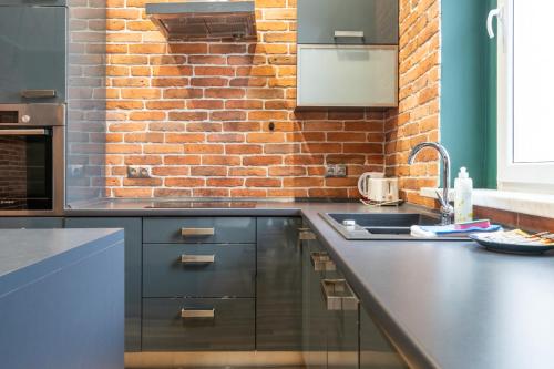 a kitchen with black cabinets and a brick wall at Żwirki i Wigury Comfort Apartment in Katowice