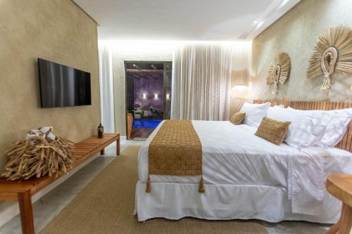 een slaapkamer met een bed en een tv aan de muur bij Pousada Mirai in São Miguel dos Milagres