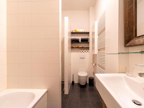 een badkamer met een bad, een wastafel en een toilet bij Cozy forest villa on the water near Harderwijk in Zeewolde