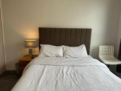 łóżko z drewnianym zagłówkiem oraz stół z lampką w obiekcie Private room in Glasgow City Center w Glasgow