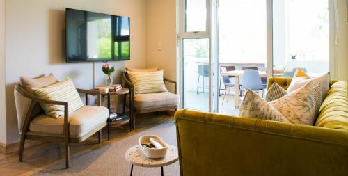 un soggiorno con divano giallo e sedie di Collection Luxury Accommodation: 7 On Murray Apartment 7 a Stellenbosch