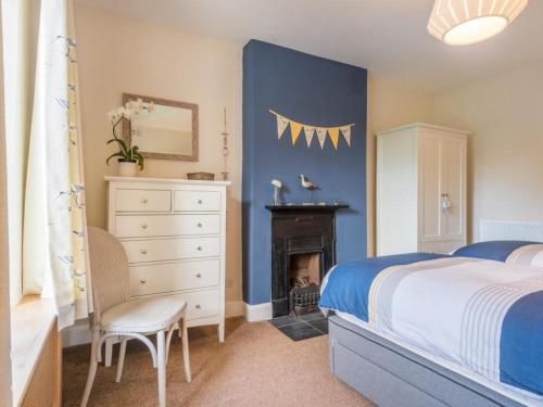 a bedroom with a bed and a dresser and a fireplace at 2 Bed in Ravenglass SZ514 in Ravenglass