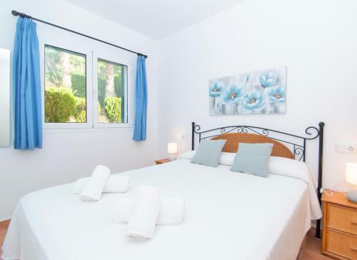 a bedroom with two white beds and blue curtains at Villa Mirador A by Sonne Villas in Cala Galdana