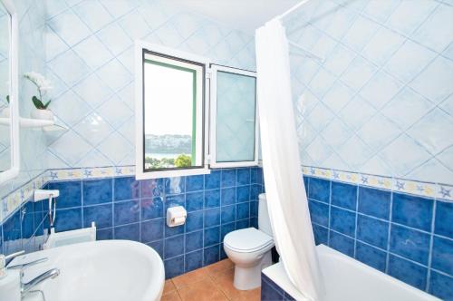 Baño de azulejos azules con aseo y lavamanos en Villa Mirador A by Sonne Villas, en Cala Galdana