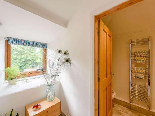een badkamer met een vaas met bloemen in een raam bij 1 Bed in Holywell 83270 in Whitford