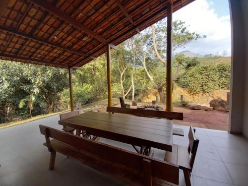 a table and benches in a room with a view at Reserva Som das Águas in Caparaó Velho