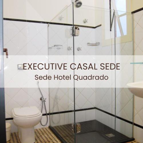 a bathroom with a toilet and a glass shower stall at Hotel Quadrado in Santa Bárbara