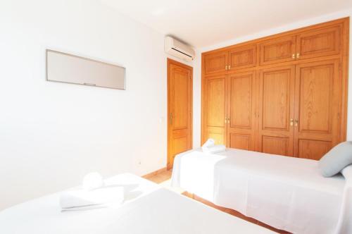 a bedroom with two white beds and wooden cabinets at Villa Mirador B by Sonne Villas in Cala Galdana